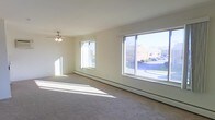 This 1-bedroom, 1-bathroom Canterbury unit is a well-lit, single-floor residence designed for comfortable everyday living. The living area is a standout feature of the space, showcasing large picture windows that flood the room with abundant natural light and offer pleasant views of the surrounding neighborhood, including green landscaping and nearby buildings. The generous window placement creates an airy, open atmosphere throughout the day. Soft carpet flooring runs through the living area, adding warmth underfoot, while a ceiling fan overhead provides both functional air circulation and a touch of classic style. Baseboard heating runs along the exterior walls, ensuring efficient and consistent warmth throughout the cooler months. The neutral, light-toned walls provide a clean and versatile backdrop, making the space easy to personalize. The overall layout is straightforward and practical, with a single-floor design that ensures seamless accessibility between rooms. This unit at Canterbury offers a bright, cozy, and functional living environment suited for those seeking a modest yet comfortable residential space.