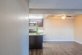 This single-floor unit offers a practical and comfortable layout designed for everyday living. The open-concept living area is finished with durable, dark hardwood-style flooring that runs throughout the main space, complemented by warm neutral-toned walls and a textured ceiling. A ceiling fan keeps the living area comfortable, while a sliding glass door floods the room with natural light and provides direct access to a private outdoor patio, framed by vertical blinds for added privacy.

The galley-style kitchen is thoughtfully designed with dark espresso cabinetry, light-toned countertops, and a double stainless steel sink. Stainless steel appliances — including a refrigerator and microwave — add a modern touch, while a dedicated pantry closet at the end of the kitchen provides generous storage space. The kitchen opens to the living area via a peninsula, creating a connected, social atmosphere.

The bedroom is carpeted for warmth and comfort, featuring neutral walls and a window that brings in natural light. The space is clean and versatile, offering a peaceful retreat.

Overall, the unit presents a cohesive, move-in ready environment with a consistent neutral color palette, efficient use of space, and functional finishes throughout, making it an inviting and practical place to call home.