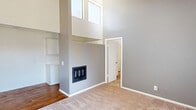 Located at 1200 West Gonzales Road in Oxnard, California, this one-bedroom, one-bathroom residence offers a thoughtfully laid-out single-floor plan with a surprisingly open feel. The living area immediately impresses with its dramatically tall ceilings and high clerestory windows that invite an abundance of natural light. A wall-mounted heater serves as a functional focal point, while the flooring transitions between warm hardwood and plush carpet, adding textural variety to the space. The open vertical volume creates an airy ambiance that makes the living area feel more expansive than its footprint suggests. The kitchen is efficiently designed with white cabinetry, speckled countertops, a stainless steel sink, and white appliances including a range and over-the-range microwave — all set atop hardwood flooring for easy maintenance. The bedroom features exposed beam ceilings with a shiplap-style finish, adding a charming architectural touch. Mirrored sliding closet doors reflect light throughout the room, which is finished with soft carpet and includes its own wall heater. The bathroom is clean and functional, equipped with a combined shower and tub with a white surround, a toilet, and a towel bar — all finished in crisp white tones for a bright, tidy feel.