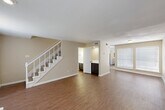 This two-story, 2-bedroom, 3-bathroom home in Houston, TX offers a well-organized layout spread across two floors. The main level features a combined dining and living area with warm wood-look flooring, neutral beige walls, and abundant natural light from large windows with blinds. A standout white brick fireplace anchors the living room, adding character and charm. The kitchen is equipped with dark cabinetry, a subway tile backsplash, a double-basin sink, and black appliances, with direct access to a dedicated laundry room housing a full-size washer and dryer. A pantry adds extra storage convenience on this level. A carpeted staircase with a white banister leads to the upper floor, where both bedrooms are located. Each bedroom features plush carpet, a ceiling fan, and closet access. The generously sized primary bedroom includes natural light from a large window. The bathrooms are finished with dark vanity cabinetry and marble-look countertops. With seven closets throughout, storage is plentiful. A private patio completes the home, offering outdoor space. The neutral color palette and functional layout make this a practical and comfortable residence.
