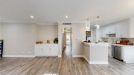 Located in the desirable Studio City neighborhood of Los Angeles, this well-appointed 2-bedroom, 2-bathroom single-story home offers a thoughtfully designed layout with modern finishes throughout. The open-concept living and kitchen area is bright and welcoming, featuring wood-look luxury flooring, recessed lighting, and elegant crown molding that adds a refined touch. A built-in white cabinetry unit in the living area provides both style and functional storage. Large windows with vertical blinds allow ample natural light to fill the space. The kitchen is efficiently designed with crisp white shaker cabinets, a tile backsplash, quartz countertops, and a full suite of stainless steel appliances, including a refrigerator, range, and dishwasher. Both bedrooms are carpeted and generously sized, each benefiting from natural light through wide windows. Three closets, including walk-in options, offer exceptional storage. The primary bathroom features a wide quartz vanity, large mirror, and a glass-enclosed shower. The second bathroom includes a shower-tub combo with a sliding glass door. A hallway connects the private quarters to the main living spaces, ensuring a practical and comfortable flow throughout the home.