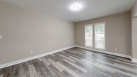 Located at 7700 Colquitt Rd in Atlanta, GA, this well-appointed 3-bedroom, 1-bathroom unit offers a thoughtfully designed single-floor layout with modern updates throughout. The open living area features gray-toned luxury vinyl plank flooring and neutral warm-beige walls that create a clean, cohesive aesthetic. A stylish pendant light fixture illuminates the entryway, which flows naturally into the living space. The kitchen is efficiently designed with gray shaker-style cabinetry, white quartz countertops, a classic white subway tile backsplash, a matte black faucet, and stainless steel appliances. A pass-through window connects the kitchen to the living area, enhancing the open feel. The generously sized primary bedroom features plush carpeting, a ceiling fan, and large windows with outdoor views, while the additional bedrooms offer similar comfort with vinyl plank or carpet flooring and ample natural light. The full bathroom is a standout feature, showcasing floor-to-ceiling white subway tile surrounding a soaking tub and shower combination with sleek matte black fixtures. A dedicated closet and an enclosed porch with large windows and green outdoor views round out this well-designed, move-in-ready home.