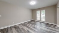 Located at 7700 Colquitt Rd in Atlanta, GA, this well-appointed 3-bedroom, 1-bathroom unit offers a thoughtfully designed single-floor layout with modern updates throughout. The open living area features gray-toned luxury vinyl plank flooring and neutral warm-beige walls that create a clean, cohesive aesthetic. A stylish pendant light fixture illuminates the entryway, which flows naturally into the living space. The kitchen is efficiently designed with gray shaker-style cabinetry, white quartz countertops, a classic white subway tile backsplash, a matte black faucet, and stainless steel appliances. A pass-through window connects the kitchen to the living area, enhancing the open feel. The generously sized primary bedroom features plush carpeting, a ceiling fan, and large windows with outdoor views, while the additional bedrooms offer similar comfort with vinyl plank or carpet flooring and ample natural light. The full bathroom is a standout feature, showcasing floor-to-ceiling white subway tile surrounding a soaking tub and shower combination with sleek matte black fixtures. A dedicated closet and an enclosed porch with large windows and green outdoor views round out this well-designed, move-in-ready home.