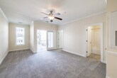 This single-floor residence offers a thoughtfully designed layout that balances comfort and functionality throughout its living spaces. The interior is finished with warm, neutral tones on the walls, complemented by elegant crown molding that runs throughout, lending a refined architectural touch to each room.

The kitchen is equipped with rich wood cabinetry, granite countertops, a double stainless steel sink, and black appliances including a refrigerator and range. A large window fills the space with natural light and provides views of the surrounding exterior. An adjacent dining area features tile flooring and an elegant chandelier, creating an inviting space for meals. The open sightline between the dining area and kitchen enhances the sense of connectivity and space.

The living area transitions seamlessly from tile to plush carpet, and is topped with a ceiling fan for added comfort. Crown molding continues here, reinforcing the cohesive design of the home. The carpeted bedroom is generously sized, offering direct access to a well-appointed en-suite bathroom complete with a tub-shower combination, a granite-topped vanity with wood cabinetry, and tile flooring. A closet provides practical storage within the bedroom. Throughout the residence, clean white trim and baseboards frame each room with a classic, polished finish.