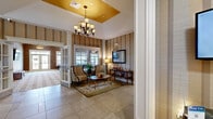 Located at 1000 Meadow Ln in Canonsburg, PA, this generously sized single-floor amenity center spans an expansive footprint across seven distinct spaces, each thoughtfully designed to serve a variety of community needs.

The welcoming lobby sets a refined tone with large-format tile flooring, bold striped wallcovering, and a striking tray ceiling accented in warm gold. An elegant chandelier anchors the space, while decorative columns and a seating area with accent chairs create an inviting first impression. The adjacent lounge continues the sophisticated aesthetic, featuring a fireplace with a crisp white surround, patterned carpet, crown molding, and ample natural light streaming through large windows with views to the outdoors.

The full kitchen is well-appointed with dark espresso cabinetry, granite countertops, stainless steel appliances, and a tile backsplash — ideal for events and gatherings. A separate dining area with multiple seating arrangements and glass door access to the exterior offers a flexible space for group functions.

A dedicated media room provides a large projection screen, surround-sound speaker placement, and plush carpeting for an immersive viewing experience. The fitness center is well-equipped with cardio machines, strength equipment, wall-mounted TVs, mirrored walls, and abundant natural light. A package locker system is also conveniently located within the fitness area.