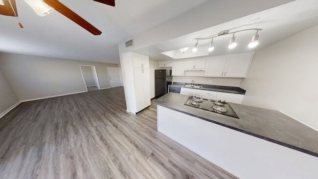 Open-plan kitchen and living area with sleek countertops, modern lighting, and elegant wood flooring. - Oak Park