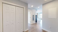 Located on the fifth floor at 210 Main St in Hackensack, NJ, this two-bedroom, two-bathroom apartment blends modern finishes with industrial character across a thoughtfully designed single-floor layout. The open-concept kitchen is a standout, featuring sleek white cabinetry extending to the ceiling, stainless steel appliances including a refrigerator, electric range, and microwave, a white subway tile backsplash, and a generous island with quartz-style countertops. Light wood-tone flooring runs throughout, unifying the living spaces. Striking exposed red brick accent walls add warmth and texture, particularly in the kitchen and primary bedroom areas. Multiple large windows fill the unit with natural light while offering elevated views of the Hackensack cityscape. The spacious primary bedroom includes two double bi-fold closets, providing ample storage. Both bathrooms are finished with large-format tile flooring, white subway tile tub surrounds with decorative mosaic border accents, chrome fixtures, and wood-toned vanities with white countertops. The second bedroom features a city-facing window and hardwood floors. A connecting hallway provides a clean transition between the living areas and bedrooms, completing this well-appointed urban residence.
