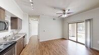 This 470 square foot, one-bedroom apartment in Austin, Texas, offers a blend of comfort and contemporary design. The open-concept layout maximizes the use of space, creating a seamless flow between living areas. The main living space boasts warm wood-look flooring and is illuminated by natural light from a large sliding glass door leading to a private balcony.

The bedroom, spanning an impressive 390 square feet, features plush carpeting and a ceiling fan for added comfort. Built-in shelving in the hallway provides additional storage options. The bathroom is efficiently designed with a granite-topped vanity and ample cabinet space. A standout feature is the in-unit laundry area, complete with full-sized, stacked washer and dryer units.

The kitchen, while not visible in the images, is likely equipped with modern appliances to complement the overall contemporary aesthetic of the apartment. Crown molding throughout adds a touch of elegance to the space. The apartment's neutral color palette allows for easy personalization, making it an ideal canvas for various decorating styles. This well-designed apartment offers a perfect balance of functionality and style for urban living in Austin.