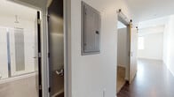 Located at 801 N Grant St in Denver's Capitol Hill neighborhood, this single-floor unit showcases a clean, modern aesthetic throughout. Rich, dark hardwood floors flow seamlessly across the open-concept living and kitchen areas, creating a cohesive and polished look.

The kitchen is well-appointed with dark espresso cabinetry extending to the ceiling for ample storage, stainless steel appliances including a range, microwave, dishwasher, and refrigerator, and a streamlined countertop with an undermount sink. Recessed lighting illuminates the space efficiently, complementing the neutral wall tones.

The living area is expansive and open, benefiting from a large window that frames views of the Denver skyline, filling the space with natural light. The hallway features a sliding barn door and a conveniently located electrical panel, adding a functional yet stylish detail to the corridor.

The bathroom is finished in a contemporary style, with a wide white countertop vanity, a dark wood cabinet base, a large mirror, and chrome fixtures. Clean, textured white walls keep the space bright and minimal.

Throughout the unit, the design emphasizes a modern urban sensibility — combining dark wood tones, neutral walls, recessed lighting, and open sightlines to create a comfortable, functional living environment in the heart of Denver.