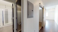 Located at 801 N Grant St in Denver's Capitol Hill neighborhood, this single-floor unit showcases a clean, modern aesthetic throughout. Rich, dark hardwood floors flow seamlessly across the open-concept living and kitchen areas, creating a cohesive and polished look.

The kitchen is well-appointed with dark espresso cabinetry extending to the ceiling for ample storage, stainless steel appliances including a range, microwave, dishwasher, and refrigerator, and a streamlined countertop with an undermount sink. Recessed lighting illuminates the space efficiently, complementing the neutral wall tones.

The living area is expansive and open, benefiting from a large window that frames views of the Denver skyline, filling the space with natural light. The hallway features a sliding barn door and a conveniently located electrical panel, adding a functional yet stylish detail to the corridor.

The bathroom is finished in a contemporary style, with a wide white countertop vanity, a dark wood cabinet base, a large mirror, and chrome fixtures. Clean, textured white walls keep the space bright and minimal.

Throughout the unit, the design emphasizes a modern urban sensibility — combining dark wood tones, neutral walls, recessed lighting, and open sightlines to create a comfortable, functional living environment in the heart of Denver.