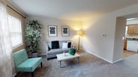 This two-story home offers a comfortable and practical layout across two well-connected levels. The living room welcomes residents with warm, neutral-toned walls, plush carpeting, and natural light filtering through large windows dressed with sheer curtains and blinds — creating a relaxed and inviting atmosphere. The adjacent dining area provides ample room for a full dining table and is accented by a ceiling fan and tasteful wall art, making it ideal for everyday meals or entertaining.

The kitchen is outfitted with warm wood cabinetry, dark granite-style countertops, and wood-look flooring. It includes a full suite of appliances — refrigerator, range, and dishwasher — and benefits from a sliding glass door that opens directly to a private outdoor patio, seamlessly blending indoor and outdoor living.

Upstairs, the bedrooms continue the home's neutral palette, each featuring plush carpet, natural light from well-positioned windows, and ample wall space. The primary bedroom is a serene retreat, while a secondary bedroom offers a cozy, light-filled environment. A full bathroom with a tub-shower combination, wood-look flooring, and clean white fixtures rounds out the upper level. Throughout the home, the design balances functionality with understated warmth.