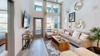 Located at 1876 Star Anise Cir in Apopka, FL, this well-appointed one-bedroom, two-bathroom residence offers a thoughtfully designed single-floor layout that maximizes both comfort and functionality. The open-concept living and kitchen area is the centerpiece of the home, featuring soaring double-height ceilings and floor-to-ceiling windows that flood the space with natural light. A private balcony extends from the living room, offering outdoor access and additional views. The kitchen is outfitted with white shaker cabinetry, grey tile backsplash, granite countertops, a large island with bar seating, stainless steel appliances including a refrigerator, range, and microwave, and elegant pendant lighting overhead. Light wood-tone flooring flows throughout the main living areas. The spacious bedroom features plush carpet, generous wall space, and direct sightlines to the kitchen area, creating a cohesive feel. Two well-sized closets with built-in wire shelving provide ample storage. Both bathrooms are finished with large-format tile, granite-topped vanities, white cabinetry, and soaking tub and shower combinations. The home is completed by a dedicated laundry area and utility room, offering practical everyday convenience.