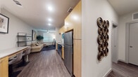 This well-appointed single-floor residence offers a thoughtfully designed layout that balances functionality with modern aesthetics. The open-concept kitchen flows seamlessly into the living area, creating a cohesive and practical space. The kitchen is outfitted with a full suite of stainless steel appliances, including a refrigerator, electric range, over-the-range microwave, and dishwasher. Light wood cabinetry pairs with granite-style countertops and a white subway tile backsplash, giving the kitchen a clean, contemporary look. Wood-look plank flooring extends throughout much of the unit, grounding the space with warmth and continuity.

The living area benefits from a large window that allows natural light to fill the room, complemented by a ceiling fan overhead. A dedicated flex space serves as an ideal home office or den, featuring a built-in desk with granite-style countertop, cabinetry below, and wood-look flooring. The bedroom is comfortably sized with its own large window and warm hardwood-style floors. The bathroom features matching light wood cabinetry, granite-style counters, and dark wood-look tile flooring, maintaining the consistent design language found throughout the unit. Overall, the space presents a cohesive, modern interior with neutral tones and practical finishes.