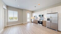 Located in Richardson, TX, this well-designed single-floor residence offers a thoughtful layout across one bedroom, one bathroom, a kitchen, and a closet. The open-concept living and kitchen area is anchored by light wood-tone flooring and neutral walls, creating a bright, cohesive atmosphere. The kitchen is outfitted with stainless steel appliances — including a refrigerator with ice maker, range, over-the-range microwave, and dishwasher — paired with two-tone cabinetry featuring white upper cabinets and warm wood-finish lower cabinets. A grey subway tile backsplash adds a clean, modern touch. The bedroom is carpeted and bathed in natural light through a window with horizontal blinds overlooking the surrounding neighborhood. A ceiling fan keeps the space comfortable, and a door connects directly to the bathroom. The bathroom features warm wood-toned cabinetry with a mirror, and a soaking tub enclosed by classic white square subway tiles with a decorative mosaic niche inset — a refined detail that elevates the overall feel. A dedicated closet and an in-unit washer and dryer complete this practical and polished Richardson residence.