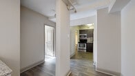 Located in the heart of downtown Nashville on Rep. John Lewis Way N, this two-bedroom, one-bathroom unit offers a functional and modern layout across a single floor. Wood-style plank flooring runs throughout the space, lending a cohesive and contemporary feel to every room.

The kitchen is a standout feature, outfitted with dark espresso cabinetry, granite-style countertops, and a full suite of stainless steel appliances including a range, microwave, dishwasher, and refrigerator. The layout maximizes counter and storage space efficiently.

Connected hallways guide you through the unit to both bedrooms, each benefiting from natural light through large windows dressed with horizontal blinds. Both bedrooms include ceiling fans, individual wall-mounted HVAC units, and closet storage. The primary bedroom offers a comfortable footprint with room for standard furnishings.

The bathroom is clean and well-appointed, featuring a soaking tub with tiled surround, a dark wood vanity with granite countertop, and wood-style flooring that ties the space together. Textured ceilings and exposed overhead piping in the hallway area add an industrial character to the overall aesthetic, giving the unit a distinctive urban edge befitting its downtown Nashville location.