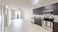 Located at 2101 Ludlam Rd in West Miami, FL, this one-bedroom, one-bathroom unit offers a well-designed layout across a single floor. The open-concept living and kitchen area is finished with large-format white tile flooring that enhances the bright, airy feel of the space. The kitchen is outfitted with dark espresso cabinetry, granite countertops, a patterned tile backsplash, and a full suite of stainless steel appliances including a refrigerator with ice maker, electric range, microwave, and dishwasher. Track lighting overhead adds both function and a modern touch. The living area is bathed in natural light from floor-to-ceiling sliding glass doors that open to a private balcony, with a ceiling fan adding comfort year-round. The spacious primary bedroom features warm light wood laminate flooring, neutral walls, a ceiling fan with natural light from a large window, and direct access to a dedicated closet. The bathroom is finished with tile flooring, a granite-topped dark wood vanity, a large mirror, and a tiled tub-shower combination. Clean lines, neutral tones, and consistent modern finishes throughout give this unit a cohesive and contemporary character.