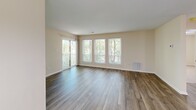 Located at 8799 Old Colony Way in Alexandria, VA, this well-appointed 2-bedroom, 2-bathroom unit offers a functional and comfortable single-floor layout. The open-concept living and dining area is bright and airy, featuring wood-style plank flooring and a wall of windows alongside a sliding glass door that leads to a private balcony overlooking lush, mature trees. The kitchen is equipped with warm-toned wood cabinetry, dark granite-style countertops, white appliances including a refrigerator, electric range, built-in microwave, and dishwasher, all anchored by a peninsula with a double sink — ideal for both cooking and casual dining. A dedicated laundry room provides in-unit washer and dryer hook-ups with built-in wire shelving for added storage. The generously sized primary bedroom features plush carpeting, natural light from multiple windows, and dual closets offering ample storage. The second bedroom, also carpeted, is a versatile space with hardwood-style flooring in the hallway. The bathrooms include a clean, all-white walk-in shower stall with chrome fixtures. Neutral wall tones and consistent finishes throughout give the unit a cohesive and move-in-ready appeal.