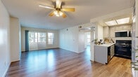 Located at 930 Figueroa Terrace in Los Angeles, this two-bedroom, one-bathroom unit offers a well-organized single-level layout with consistent wood-style flooring throughout every room. The living area is bright and open, anchored by a ceiling fan and a sliding glass door that leads to a balcony with views of the surrounding neighborhood, allowing generous natural light to fill the space. A second access point via large corner windows further enhances the airy atmosphere.

The kitchen is efficiently designed with gray cabinetry, light stone countertops, a stainless steel refrigerator and microwave, and a black gas range, providing a functional and modern cooking environment. The primary bedroom features a mirrored sliding-door closet that adds depth to the room, along with windows overlooking the exterior. The second bedroom is bright and clean, with its own windows framing outdoor views. Both rooms are finished with the same warm wood-style flooring found throughout the unit.

The bathroom is well-appointed with a combined tub and shower, a wall-mounted vanity with mirror, and accessibility grab bars. A hallway connects the main living areas, contributing to a logical and efficient floor plan. The unit's neutral cream walls and cohesive flooring create a clean, move-in-ready aesthetic throughout.