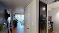 This single-floor residence showcases a thoughtfully curated interior with a cohesive modern-eclectic aesthetic. The entry hallway, finished with warm hardwood-style flooring, leads into an open-concept living and dining area that serves as the heart of the home. The living room is bright and inviting, featuring sheer floor-to-ceiling curtains that filter natural light, a ceiling fan, track lighting, and a sliding glass door opening to an outdoor patio. The space is accented by blue-toned walls, an array of framed wall art, and lush indoor plants that add warmth and texture.

Adjacent to the living area, the dining space includes a round marble-top table and connects seamlessly to the kitchen. The kitchen is a standout feature, outfitted with dark lower cabinetry, white upper cabinets, dark countertops, stainless steel appliances, and a bold geometric patterned tile backsplash that adds a striking visual element.

The two bedrooms each carry their own distinct character. One bedroom features a dramatic geometric blue accent wall paired with desert-themed artwork and a ceiling fan. The second bedroom features a two-tone wall treatment in grey and blue, a mirrored sliding closet, and sheer curtains that allow ample natural light. Both rooms are finished with hardwood-style flooring.