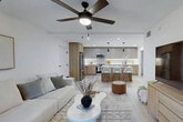 Located at 3101 Village Blvd in West Palm Beach, FL, this thoughtfully designed one-bedroom, one-bathroom residence offers a seamless open-concept layout that connects the living, dining, and kitchen areas into a cohesive, airy space. Light-toned luxury vinyl plank flooring runs throughout, complementing the bright white walls and creating a clean, modern aesthetic.

The kitchen is a standout feature, showcasing a two-tone cabinetry design with warm wood lower cabinets and matte upper cabinets, under-cabinet LED lighting, white quartz countertops, stainless steel appliances, and a central island with pendant lighting and bar seating. The living area is anchored by large sliding glass doors that open to a private patio, allowing natural light to flood the space and offering outdoor access.

The bedroom is a comfortable retreat, featuring a ceiling fan, a window with exterior views, and ample closet storage — with four closets distributed throughout the residence. The bathroom includes a full tub-shower combination, a wood-vanity with a white countertop, and clean tile finishes. A dedicated in-unit laundry room with a full-size washer and dryer adds practical convenience. Ceiling fans in both the living area and bedroom enhance comfort throughout this well-appointed West Palm Beach home.