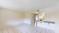 Located at 744 Spring West Rd in Orlando, FL, this one-bedroom, one-bathroom unit offers a practical and well-organized single-floor layout. The open-concept living and dining area is finished with large, light-toned ceramic tiles that run throughout the common spaces, creating a clean and cohesive look. Warm cream-colored walls and a textured ceiling complement the bright, airy feel of the space. A window in the living area allows natural light to flow in, offering views of the surrounding greenery.

The kitchen is positioned adjacent to the living area and features a peninsula-style breakfast bar with granite countertop, white cabinetry, and a white appliance suite including a gas range. The layout promotes an efficient use of space while maintaining an open connection to the main living area.

The bedroom is carpeted for comfort and is notably bright, thanks to sliding glass doors that open onto a private balcony with outdoor views. Built-in shelving beside the balcony doors provides convenient storage, and the room connects directly to a dedicated closet.

The bathroom is finished with matching tile flooring, a granite vanity countertop with white cabinetry, and a full shower-tub combination, maintaining a consistent, clean aesthetic throughout the unit.