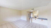 Located at 744 Spring West Rd in Orlando, FL, this one-bedroom, one-bathroom unit offers a practical and well-organized single-floor layout. The open-concept living and dining area is finished with large, light-toned ceramic tiles that run throughout the common spaces, creating a clean and cohesive look. Warm cream-colored walls and a textured ceiling complement the bright, airy feel of the space. A window in the living area allows natural light to flow in, offering views of the surrounding greenery.

The kitchen is positioned adjacent to the living area and features a peninsula-style breakfast bar with granite countertop, white cabinetry, and a white appliance suite including a gas range. The layout promotes an efficient use of space while maintaining an open connection to the main living area.

The bedroom is carpeted for comfort and is notably bright, thanks to sliding glass doors that open onto a private balcony with outdoor views. Built-in shelving beside the balcony doors provides convenient storage, and the room connects directly to a dedicated closet.

The bathroom is finished with matching tile flooring, a granite vanity countertop with white cabinetry, and a full shower-tub combination, maintaining a consistent, clean aesthetic throughout the unit.