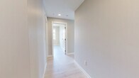 Located at 7 Erskine Lane in Victoria, BC, this well-appointed 3-bedroom, 2-bathroom unit offers a thoughtfully designed single-level layout with a clean, contemporary aesthetic throughout. Light hardwood flooring flows seamlessly across the entire space, complemented by neutral warm-grey walls and crisp white trim.

The open-concept kitchen and living area serves as the heart of the home, featuring a large central island with a white quartz countertop and natural wood-toned cabinetry. The kitchen is equipped with stainless steel appliances, white upper cabinetry, and recessed lighting, with a window bringing in natural light and treetop views.

The primary bedroom is generously proportioned, boasting floor-to-ceiling windows on two walls that frame sweeping views of the surrounding Victoria landscape and skyline, flooding the room with abundant natural light. The additional bedrooms are well-sized and bright, each featuring light hardwood floors and built-in sliding closets with clean white panelled doors. A wall-mounted mini-split unit provides efficient climate control.

Both bathrooms are finished with dark marble-effect tile flooring and light wood vanity cabinetry paired with white quartz counters. One bathroom features a glass-enclosed walk-in shower, while the other includes a full soaker tub. In-suite stacked laundry is also conveniently included.