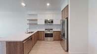 Located at 800 S Harvard Blvd in the heart of Los Angeles, this modern single-floor unit offers a thoughtfully designed layout with contemporary finishes throughout. The kitchen is a standout feature, showcasing a sleek combination of white upper cabinetry and warm wood-toned lower cabinets, complemented by a hexagonal tile backsplash, quartz countertops, stainless steel appliances, and open floating wood shelves that add a touch of warmth and practicality. Recessed lighting enhances the clean, modern aesthetic.

The bedrooms are bright and airy, each featuring light hardwood-style flooring and large windows that invite abundant natural light while offering views of the surrounding Los Angeles neighborhood and city skyline. The clean white walls create a neutral, versatile canvas throughout.

The bathroom is finished to a high standard, with dark tile flooring, a wood-grain vanity with a white quartz countertop, an undermount sink, and a backlit frameless mirror that adds a refined, contemporary touch.

A generously sized walk-in closet provides ample storage, equipped with double hanging rods, built-in shelving, and hardwood-style flooring, offering an organized and functional space. Overall, the unit presents a clean, modern living environment well-suited to urban Los Angeles living.