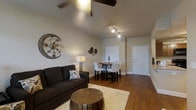 This well-appointed 1-bedroom, 1-bathroom residence offers a thoughtfully designed single-floor layout that maximizes every inch of its intimate footprint. The open-concept living and dining area serves as the heart of the home, highlighted by striking vaulted ceilings that lend a sense of openness and volume beyond what the square footage might suggest. Rich hardwood flooring runs throughout, adding warmth and visual continuity across the main living spaces. A ceiling fan with overhead lighting anchors the living area, complemented by track lighting that provides flexible illumination for the dining space. Neutral-toned walls create a clean, versatile backdrop, while decorative wall accents and tasteful furnishings contribute a modern yet inviting ambiance. The dining area comfortably accommodates a small table and chairs, positioned conveniently near the entryway. The layout flows naturally from the living area toward the private bedroom and bathroom, offering a practical and comfortable arrangement. With its combination of vaulted ceilings, hardwood floors, and open living design, this residence presents a bright and functional space well-suited for comfortable everyday living.