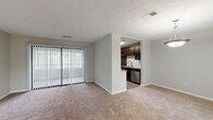 Located at 6937 Roswell Rd in Sandy Springs, GA, this single-floor residence offers a well-organized layout designed for comfortable living. The open living area is generously sized, featuring neutral-toned carpet, soft gray walls, and a sliding glass door fitted with vertical blinds that fills the space with natural light while providing access to the outdoors. The living area flows conveniently toward a separate dining space, illuminated by a pendant light fixture and brightened by multiple windows.

The galley-style kitchen is a functional highlight, featuring rich dark-espresso cabinetry, granite countertops, a white subway tile backsplash, and wood-look flooring. Stainless steel appliances — including a refrigerator, range, microwave, and dishwasher — complete the well-equipped space. A window at the far end of the kitchen adds natural light.

The bedrooms are carpeted and spacious, each with natural light from windows, closet storage, and textured ceilings. One bedroom includes a ceiling fan for added comfort. The bathroom features dark-wood cabinetry, a large framed mirror, a bright vanity light fixture, and wood-look tile flooring, with a separate toilet and tub/shower area.