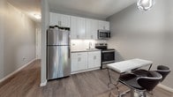 Located at 270 Laurel in Hartford, Connecticut, this thoughtfully designed studio unit combines modern aesthetics with practical living. The open-plan layout seamlessly integrates the sleeping, living, and dining areas into one cohesive space, all finished with durable wood-look flooring in warm grey tones that lend a contemporary feel throughout.

The main living area offers generous room for both a full-sized bed and a sectional sofa, with neutral grey walls creating a calm and versatile backdrop. A sleek pendant light fixture adds a stylish focal point, while a window with a roller shade invites natural light and provides views of the surrounding greenery.

The kitchen is efficiently designed and well-appointed, featuring crisp white shaker cabinetry, a classic subway tile backsplash, and a full suite of stainless steel appliances including a refrigerator, electric range, and microwave. A compact dining area with a modern bar-height table and chairs connects naturally to the kitchen space.

The bathroom is finished in a clean, white palette with subway tile surround, a vanity with under-cabinet storage, a lighted mirror, and a combination tub and shower — offering a polished and functional space. Throughout the unit, consistent design choices create a cohesive, move-in ready environment ideal for comfortable urban living.