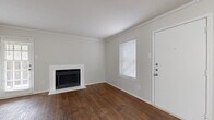 Located at 17630 Wayforest Dr in Houston, TX, this one-bedroom, one-bathroom home offers a practical and comfortable single-floor layout. Rich, dark wood-look flooring flows throughout the living areas, anchored by a white-surround fireplace that serves as a focal point in the living room. Crown molding adds a classic finishing touch, while multiple windows dressed with blinds allow natural light to brighten the space. A back door provides convenient outdoor access directly from the living area. The galley-style kitchen features white cabinetry, granite-look countertops, a stainless steel sink, and a dishwasher, making efficient use of the available space. The bedroom is generously proportioned, equipped with a ceiling fan and light fixture, and opens directly into a spacious walk-in closet outfitted with built-in shelving and hanging rods on multiple walls, offering ample storage. A second closet provides additional storage elsewhere in the home. The full bathroom includes a single-sink vanity with granite-look countertops, a toilet, and a tub-shower combination. Wood-look flooring continues into the bathroom, maintaining a cohesive aesthetic. A hallway connects the rooms efficiently, completing this well-organized and functional home.