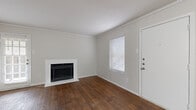 Located at 17630 Wayforest Dr in Houston, TX, this one-bedroom, one-bathroom home offers a practical and comfortable single-floor layout. Rich, dark wood-look flooring flows throughout the living areas, anchored by a white-surround fireplace that serves as a focal point in the living room. Crown molding adds a classic finishing touch, while multiple windows dressed with blinds allow natural light to brighten the space. A back door provides convenient outdoor access directly from the living area. The galley-style kitchen features white cabinetry, granite-look countertops, a stainless steel sink, and a dishwasher, making efficient use of the available space. The bedroom is generously proportioned, equipped with a ceiling fan and light fixture, and opens directly into a spacious walk-in closet outfitted with built-in shelving and hanging rods on multiple walls, offering ample storage. A second closet provides additional storage elsewhere in the home. The full bathroom includes a single-sink vanity with granite-look countertops, a toilet, and a tub-shower combination. Wood-look flooring continues into the bathroom, maintaining a cohesive aesthetic. A hallway connects the rooms efficiently, completing this well-organized and functional home.