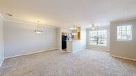 Located at Summit Pointe in Greenwood, Indiana, this single-floor, 2-bedroom, 2-bathroom residence offers a thoughtfully designed layout with a cohesive, neutral aesthetic throughout. The open-concept living and kitchen area forms the heart of the home, where plush carpeting flows through the living space beneath crown molding. A ceiling fan provides comfort, while a large window invites natural light and outdoor views of the surrounding community.

The kitchen is equipped with warm wood cabinetry, light stone-look countertops, black appliances, and hardwood-style flooring. A peninsula with pendant lighting connects the kitchen to the living area, creating an efficient, social layout. A double-basin sink sits beneath additional windows, keeping the space bright.

The spacious primary bedroom features carpet, a ceiling fan, and a sliding glass door with exterior access. Its en-suite bathroom includes a wood-tone vanity with stone countertop, a tub/shower combo, and hardwood-style flooring. The second bedroom is carpeted and well-proportioned. A second full bathroom mirrors similar finishes with a single vanity and hardwood-style flooring. Crown molding and consistent neutral tones lend a cohesive feel throughout.
