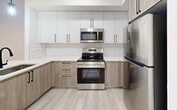 Located at 18412 Homestead Ave, Unit 218, in Miami, FL, this well-designed one-bedroom, one-bathroom residence offers a thoughtfully laid-out floor plan that maximizes every square foot of its compact footprint. The interior presents a cohesive modern aesthetic, with light wood-style luxury vinyl flooring and crisp white walls flowing throughout the space.

The kitchen is a standout feature, showcasing a two-tone cabinetry scheme that pairs white upper cabinets with warm wood-finish lower cabinets, accented by matte black hardware. A white quartz countertop extends to form a peninsula with a built-in sink, creating a functional breakfast bar and pass-through. Stainless steel appliances — including a refrigerator, electric range, and over-the-range microwave — complete the polished look. A subway tile backsplash and a pendant light fixture add refined detail.

The bedroom is a calm, bright retreat with a large window fitted with a roller shade, allowing for natural light control and privacy. Clean white walls and the same light flooring continue into this space, creating a serene atmosphere.

The bathroom features neutral large-format tile in the shower/tub surround and on the floor, complemented by a white vanity with black hardware, offering a spa-like feel. The overall ambiance of the unit is modern, clean, and move-in ready.