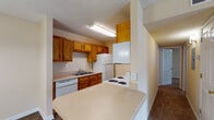 Located at 1610 Clover St in Louisville, Kentucky, this single-story residence offers a practical and well-organized layout designed for comfortable everyday living. The kitchen serves as a functional hub of the home, featuring warm oak cabinetry that extends to the ceiling for ample storage, light-toned countertops, and a full suite of white appliances including a coil-burner range, refrigerator, dishwasher, and over-the-range microwave. The galley-style configuration maximizes efficiency, with durable wood-look vinyl flooring running underfoot. A peninsula counter connects the kitchen to the adjacent dining area, which is accented by a gold-toned chandelier overhead — an inviting space for meals and gatherings. The living room is generously sized with plush carpeting, a ceiling fan, and a window that brings in natural light. The bedrooms continue the carpeted, neutral-toned aesthetic, each equipped with ceiling fans or overhead lighting and windows that offer views of the surrounding greenery. A centrally located hallway with wood-look flooring provides convenient access to the bedrooms and bathroom, which includes a vanity with light countertops. Textured ceilings and warm beige walls create a cohesive, understated ambiance throughout the home.
