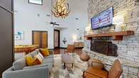 Campus Lodge Columbia's clubhouse at 2900 Old US Highway 63 S in Columbia, Missouri is a single-story community hub designed with a rustic-modern aesthetic. The space is defined by dramatic soaring ceilings throughout, with high clerestory windows that flood the interiors with abundant natural light.

The central lounge area serves as the heart of the clubhouse, anchored by a striking floor-to-ceiling stacked stone fireplace with a wood mantel and a mounted flat-screen TV. Comfortable seating, including a contemporary gray sectional, leather accent chairs, and leather poufs, surrounds a geometric-patterned area rug. An eye-catching antler chandelier and ceiling fans complete the inviting atmosphere.

Adjacent to the lounge is a game room featuring a rustic log-base billiards table beneath a modern pendant light fixture, with glass double doors opening to an outdoor deck area. The polished concrete floors flow seamlessly throughout the space, adding an industrial-chic character.

The front desk area provides a welcoming reception with warm wood paneling, pendant lighting, and a branded Campus Lodge rug. Nearby, a refreshment station offers residents convenient access to coffee and other amenities. Additional seating nooks and communal table areas are thoughtfully integrated throughout, making this clubhouse a versatile and well-appointed gathering space for residents.