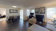 This single-floor residence offers a thoughtfully designed layout that balances comfort and functionality throughout its interconnected living spaces. The living room serves as the heart of the home, anchored by a classic fireplace and adorned with dark hardwood flooring that extends seamlessly into the dining and kitchen areas. Large windows allow natural light to fill the space, creating a warm and inviting ambiance. A sliding glass door in the dining area provides a direct connection to the outdoors, further enhancing the open feel of the main living zone.

The kitchen is well-equipped with white cabinetry, dark granite-style countertops, and a full suite of appliances including a range, microwave, and refrigerator. Ample cabinet and counter space make this an efficient and practical cooking environment.

The primary bedroom is generously proportioned, featuring plush carpeting, a sitting area, and direct access to a well-appointed en-suite bathroom. The bathroom includes a dual-sink vanity with granite-style countertops and a shower. A second bedroom offers comfortable accommodations with its own sliding glass door that opens to outdoor views, bathing the room in natural light. Together, these spaces deliver a cohesive, comfortable living experience.
