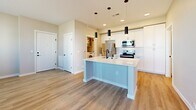 Located at 5520 Wellness Way in Santa Fe, NM, this efficiently designed one-bedroom, one-bathroom residence offers a thoughtful single-floor layout with modern finishes throughout. The open-concept kitchen serves as the heart of the home, featuring white shaker cabinetry, a white quartz waterfall island with an undermount sink and matte black faucet, white subway tile backsplash, and a full suite of stainless steel appliances including a refrigerator, electric range, built-in microwave, and dishwasher. Stylish cylindrical pendant lights add a contemporary touch above the island. Light wood-tone luxury vinyl plank flooring runs throughout the main living areas, providing a clean, cohesive aesthetic. The bedroom is a comfortable, carpeted retreat with a ceiling fan, natural light from multiple windows with blinds, and direct access to both the bathroom and a closet. The bathroom is well-appointed with a white vanity featuring matte black hardware, a tiled tub-shower surround, and matching black fixtures and towel bars. A dedicated laundry room houses a full-size Whirlpool front-loading washer and dryer. Neutral gray tones on the walls throughout create a calm, modern ambiance well-suited to Santa Fe living.