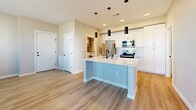 Located at 5520 Wellness Way in Santa Fe, NM, this efficiently designed one-bedroom, one-bathroom residence offers a thoughtful single-floor layout with modern finishes throughout. The open-concept kitchen serves as the heart of the home, featuring white shaker cabinetry, a white quartz waterfall island with an undermount sink and matte black faucet, white subway tile backsplash, and a full suite of stainless steel appliances including a refrigerator, electric range, built-in microwave, and dishwasher. Stylish cylindrical pendant lights add a contemporary touch above the island. Light wood-tone luxury vinyl plank flooring runs throughout the main living areas, providing a clean, cohesive aesthetic. The bedroom is a comfortable, carpeted retreat with a ceiling fan, natural light from multiple windows with blinds, and direct access to both the bathroom and a closet. The bathroom is well-appointed with a white vanity featuring matte black hardware, a tiled tub-shower surround, and matching black fixtures and towel bars. A dedicated laundry room houses a full-size Whirlpool front-loading washer and dryer. Neutral gray tones on the walls throughout create a calm, modern ambiance well-suited to Santa Fe living.