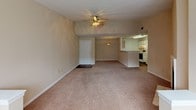 This single-floor residence offers a thoughtfully designed layout that balances comfort and functionality throughout. The spacious living room serves as the heart of the home, anchored by a tile-surround fireplace and bathed in natural light from a large bay window. Vaulted ceilings and a ceiling fan with integrated lighting enhance the airy feel of the space, while neutral-toned carpeting flows underfoot.

The living area opens seamlessly into the dining space, which connects directly to the galley-style kitchen. The kitchen features white cabinetry, light laminate countertops, a dishwasher, an electric range, and rich hardwood-style flooring — providing a clean, practical workspace for everyday use.

The residence includes multiple bedrooms, each finished with plush carpeting, ceiling fans, and ample closet space. The primary bedroom is notably generous, offering a walk-in closet and direct access to additional storage. A secondary bedroom also includes closet access and a window for natural light.

The full bathroom is clean and functional, featuring a tub/shower combination with tiled surround, a toilet, and hardwood-style flooring that complements the kitchen. Throughout the home, warm beige tones and textured ceilings create a cohesive, welcoming ambiance well-suited for comfortable everyday living.