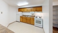Located at 9640 Fernwood Dr in Olmsted Falls, Ohio, this single-floor residence offers a straightforward and functional layout designed for comfortable everyday living. The living area is generously sized, featuring wall-to-wall carpeting and a ceiling fan with integrated lighting. A large sliding glass door fitted with vertical blinds fills the room with natural light and provides views of the surrounding greenery, creating a bright and airy atmosphere. A half-wall pass-through connects the living space to the kitchen, enhancing the open feel between the two areas. The kitchen is equipped with warm oak cabinetry both above and below the counters, a double stainless steel sink, laminate countertops, a gas range, built-in microwave, and a full-size refrigerator — all set on easy-to-maintain tile flooring. The bedroom continues the carpeted comfort of the living area and features a large window that invites natural light, along with a reach-in closet offering built-in shelving for organized storage. The full bathroom includes a single-sink vanity with a large mirror and lighted fixture, a toilet, and a tub-shower combination with white tile surround. Throughout the unit, neutral tones and clean finishes create a cohesive and welcoming environment.