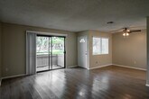 Located at 955 W 19th St in Costa Mesa, California, this well-appointed one-bedroom, one-bathroom unit is laid out entirely on a single floor, offering a functional and comfortable living environment. The main living area is open and airy, featuring light wood flooring, neutral warm-toned walls, a textured ceiling, and a ceiling fan with integrated lighting. A front entry door with an arched transom window welcomes natural light into the space, while a sliding glass door at the rear opens to a private balcony overlooking lush greenery. The combined dining and kitchen area is efficiently designed, equipped with white cabinetry, granite-style countertops, a double stainless steel sink, and a white electric range. A drop-panel ceiling with built-in lighting provides even illumination throughout the kitchen. The spacious bedroom is carpeted for comfort, features a ceiling fan, a window with vertical blinds for natural light, and includes access to two closets. The full bathroom offers a clean, bright aesthetic with a wide vanity, granite-style countertop, ample storage, and a shower-tub combination. A hallway connects the main living spaces, completing the thoughtful layout of this Costa Mesa residence.