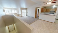 Located at 1415 Tullar Rd in Neenah, Wisconsin, this single-floor unit offers a well-organized layout designed for comfortable everyday living. The open-concept living and dining area is a standout feature, highlighted by vaulted ceilings that create a sense of height and spaciousness. Plush carpeting covers the living area, while tile flooring transitions through the entryway and kitchen zones. A sliding glass door leads to a private balcony, allowing natural light to fill the space and providing outdoor access. A ceiling fan adds to the comfort of the main living area. The kitchen is equipped with warm oak cabinetry offering generous upper and lower storage, white countertops, and an electric range with an overhead ventilation hood. Tile flooring completes the kitchen's practical finish. The bedrooms are carpeted and well-lit, with windows that bring in natural daylight; one bedroom features a vaulted ceiling and a closet with oak-trimmed doors. A dedicated laundry area with washer and dryer hookups adds everyday convenience. The bathroom includes a full tub-shower combination, tile flooring, and an oak vanity. Baseboard heating is present throughout, ensuring warmth during Wisconsin's colder months.