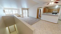 Located at 1415 Tullar Rd in Neenah, Wisconsin, this single-floor unit offers a well-organized layout designed for comfortable everyday living. The open-concept living and dining area is a standout feature, highlighted by vaulted ceilings that create a sense of height and spaciousness. Plush carpeting covers the living area, while tile flooring transitions through the entryway and kitchen zones. A sliding glass door leads to a private balcony, allowing natural light to fill the space and providing outdoor access. A ceiling fan adds to the comfort of the main living area. The kitchen is equipped with warm oak cabinetry offering generous upper and lower storage, white countertops, and an electric range with an overhead ventilation hood. Tile flooring completes the kitchen's practical finish. The bedrooms are carpeted and well-lit, with windows that bring in natural daylight; one bedroom features a vaulted ceiling and a closet with oak-trimmed doors. A dedicated laundry area with washer and dryer hookups adds everyday convenience. The bathroom includes a full tub-shower combination, tile flooring, and an oak vanity. Baseboard heating is present throughout, ensuring warmth during Wisconsin's colder months.