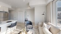 Located at 192 Erie St in Port Colborne, Ontario, this thoughtfully designed 2-bedroom, 1-bathroom unit offers a clean, modern aesthetic throughout its single-floor layout. The open-concept living and kitchen area serves as the heart of the home, featuring light hardwood-style flooring, recessed lighting, and an abundance of natural light streaming through large windows. The contemporary kitchen is equipped with stainless steel appliances, crisp white cabinetry extending to the ceiling, and a central island with a quartz countertop and breakfast bar seating — ideal for casual dining and entertaining. The living area is bright and welcoming, with oversized windows that frame outdoor views and create an airy, comfortable atmosphere. The primary bedroom is a serene retreat with a large window, plush carpeting, and a generous closet. The second bedroom features a built-in wall shelf, a sliding closet, and its own window, offering a cozy and functional space. The bathroom is finished with elegant marble-style tile surrounding a full soaker tub, complemented by clean white fixtures. Throughout the unit, the neutral colour palette, modern trim, and consistent finishes contribute to a cohesive and polished interior.
