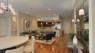 This single-floor residence showcases a thoughtfully designed open-concept layout that unifies the living, dining, and kitchen areas into one cohesive and inviting space. Rich hardwood flooring in warm tones flows continuously throughout, anchoring the interior with a sense of warmth and elegance.

The kitchen is outfitted with dark espresso cabinetry, stainless steel appliances including a refrigerator and built-in microwave, and a central island with a breakfast bar ideal for casual dining. Pendant lighting hangs above the island, adding a stylish focal point to the culinary space.

Adjacent to the kitchen, a dining area provides a comfortable setting for shared meals, while the living room features a plush sectional sofa, an upholstered armchair seating arrangement, and a coffee table set atop a neutral area rug. A striking abstract artwork adorns the wall, adding a creative accent to the space.

Recessed lighting throughout the ceiling ensures consistent, well-distributed illumination, complemented by wall sconces that contribute a softer ambient glow. A built-in HVAC system is neatly integrated into the ceiling, ensuring year-round comfort. The overall aesthetic is clean, modern, and sophisticated, with a neutral color palette that creates a calm and welcoming atmosphere.