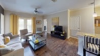 This single-floor residence is thoughtfully designed with a cohesive contemporary aesthetic, highlighted by a warm yellow and grey color palette carried throughout every room. The open-concept living and dining area features rich hardwood-style flooring, crown molding, and a ceiling fan, with French doors that invite natural light and outdoor views. A bold charcoal accent wall anchors the living space, complemented by a large statement artwork and ample room for comfortable seating arrangements.

The kitchen is well-equipped with stainless steel appliances, rich dark wood cabinetry, granite countertops, a deep double sink, and pendant lighting over the extended breakfast bar, which also connects to the dining area. Hardwood-style flooring continues seamlessly through the kitchen and both bathrooms, each of which features dark wood vanities with granite countertops. One bathroom includes a full soaking tub with a tiled surround, while the other offers a clean, efficient layout.

Both bedrooms are carpeted and generously sized, each featuring ceiling fans and large windows that fill the rooms with natural light. The primary bedroom includes a grey accent wall with framed artwork above the headboard, while the second bedroom boasts a vibrant yellow accent wall and a bold floral window treatment, adding a lively, personalized touch to the space.
