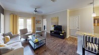 This single-floor residence is thoughtfully designed with a cohesive contemporary aesthetic, highlighted by a warm yellow and grey color palette carried throughout every room. The open-concept living and dining area features rich hardwood-style flooring, crown molding, and a ceiling fan, with French doors that invite natural light and outdoor views. A bold charcoal accent wall anchors the living space, complemented by a large statement artwork and ample room for comfortable seating arrangements.

The kitchen is well-equipped with stainless steel appliances, rich dark wood cabinetry, granite countertops, a deep double sink, and pendant lighting over the extended breakfast bar, which also connects to the dining area. Hardwood-style flooring continues seamlessly through the kitchen and both bathrooms, each of which features dark wood vanities with granite countertops. One bathroom includes a full soaking tub with a tiled surround, while the other offers a clean, efficient layout.

Both bedrooms are carpeted and generously sized, each featuring ceiling fans and large windows that fill the rooms with natural light. The primary bedroom includes a grey accent wall with framed artwork above the headboard, while the second bedroom boasts a vibrant yellow accent wall and a bold floral window treatment, adding a lively, personalized touch to the space.