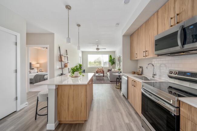 Kitchen with oak cabinetry, stainless-steel appliances, pendant lighting, hard-surface flooring and granite countertops - Avalon Westminster Promenade